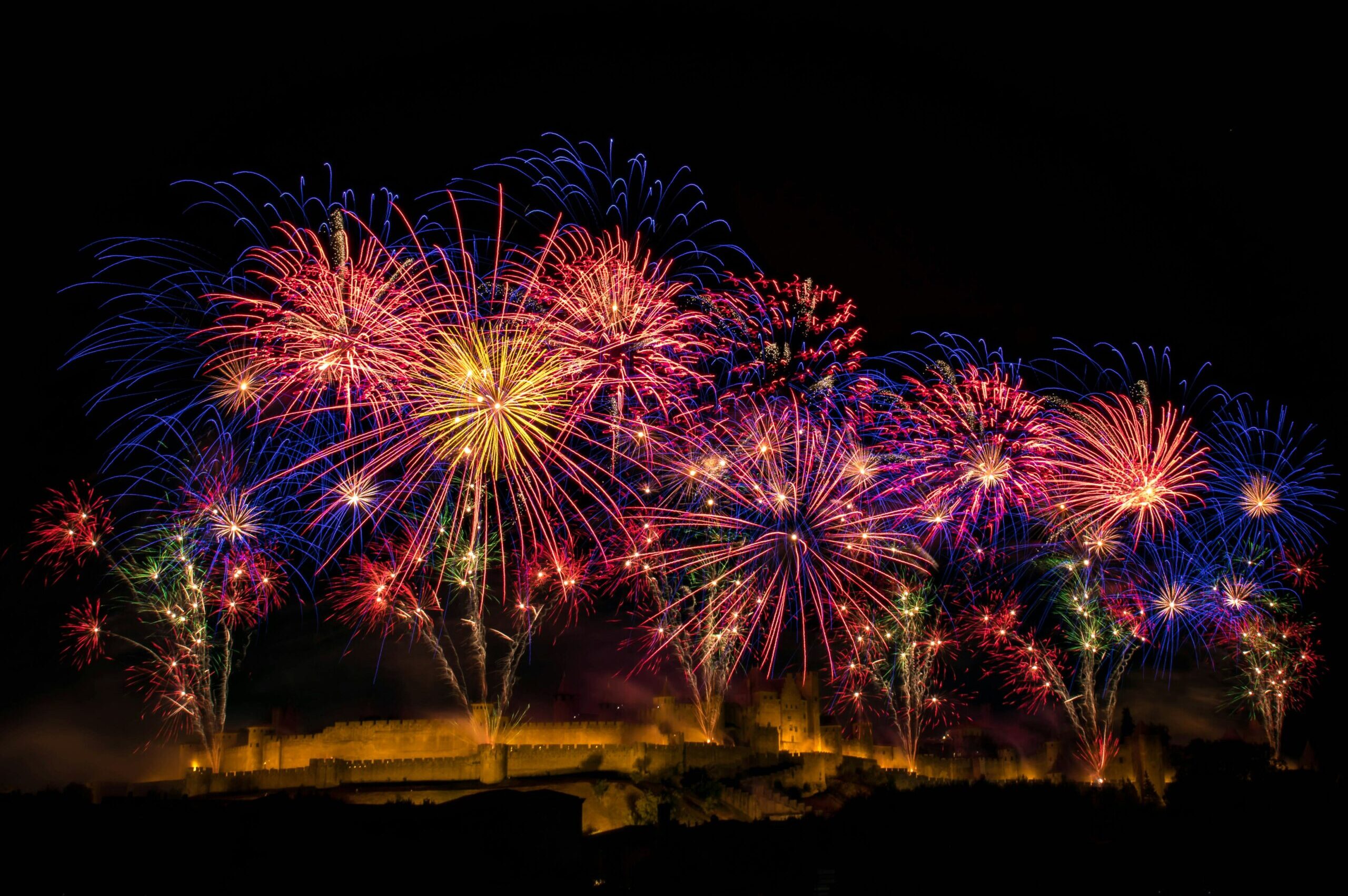 The night sky lights up with a stunning display of multicolored fireworks. If you look closely, they're being launched from a castle wall... but most people who see this image visually will probably miss that part!