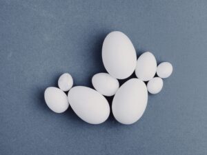 A selection of eggs clusters tastefully against a blue-grey background. They are all white, but vary in size. The difference between the smallest and the largest is appreciable, but still nowhere near the size gap between the short story you tried to write and the six-book series you ended up with.